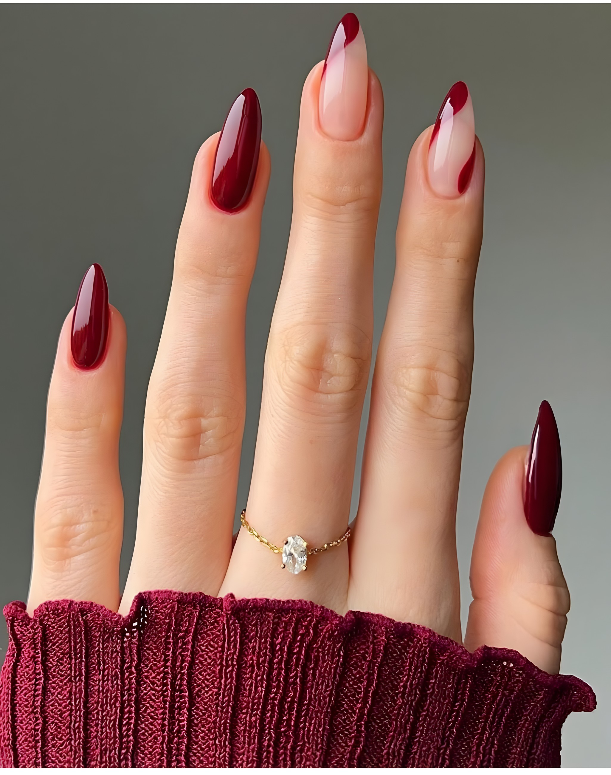 Glossy burgundy almond nails with a bare accent nail